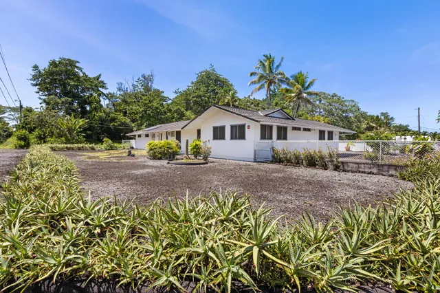 a front view of a house with a yard and potted plants