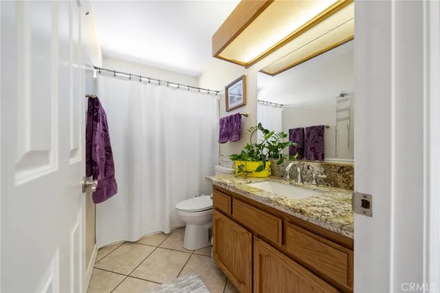 a bathroom with a granite countertop sink a toilet and shower