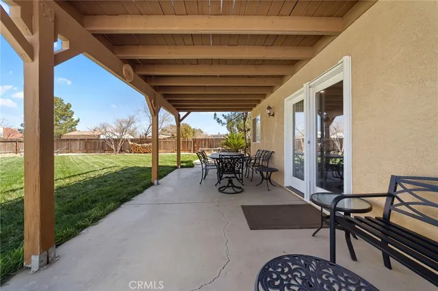 a view of a patio with table and chairs potted plants with wooden floor and fence