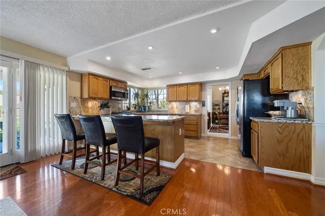 a kitchen with stainless steel appliances granite countertop a refrigerator a stove top oven a sink dishwasher and white cabinets with wooden floor