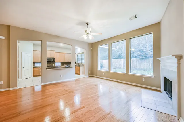 a view of an empty room with kitchen and window