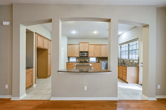 a view of a kitchen with kitchen island a refrigerator wooden floor and a view of living room