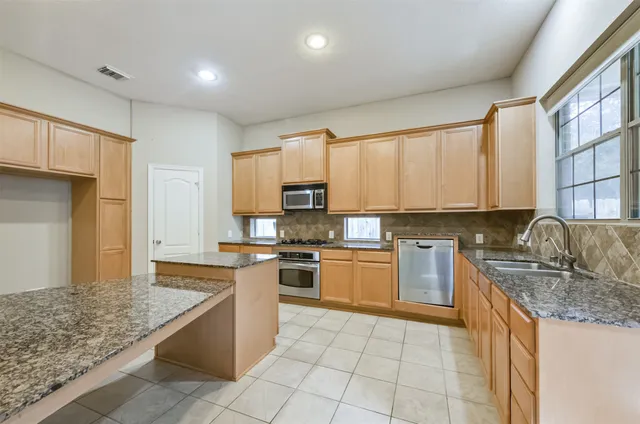 a kitchen with stainless steel appliances granite countertop a stove top oven a sink a counter top space and cabinets