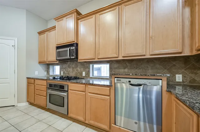 a kitchen with granite countertop cabinets stainless steel appliances and a counter space