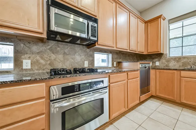 a kitchen with granite countertop stainless steel appliances a stove microwave and sink