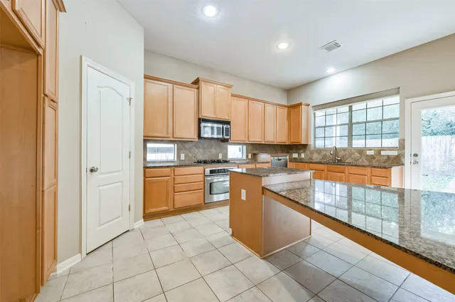 a kitchen with stainless steel appliances granite countertop a refrigerator and a stove top oven
