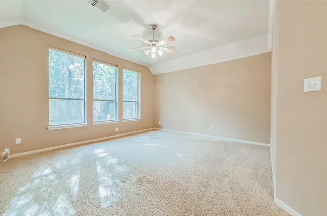 an empty room with chandelier fan and windows