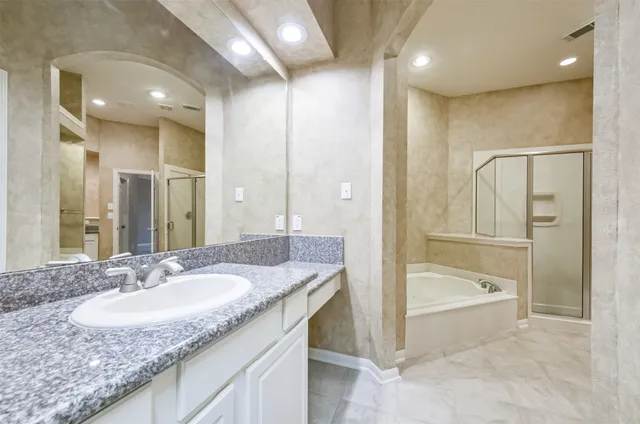a bathroom with a granite countertop sink a mirror and a bathtub