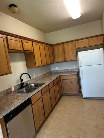 a kitchen with granite countertop a sink a stove and a refrigerator