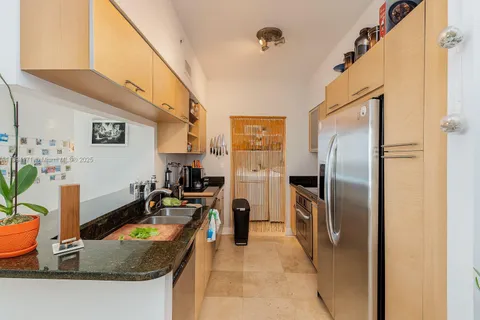 a kitchen with stainless steel appliances granite countertop a refrigerator a stove and a sink