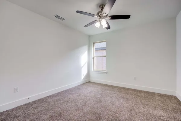 an empty room with a window and a fan
