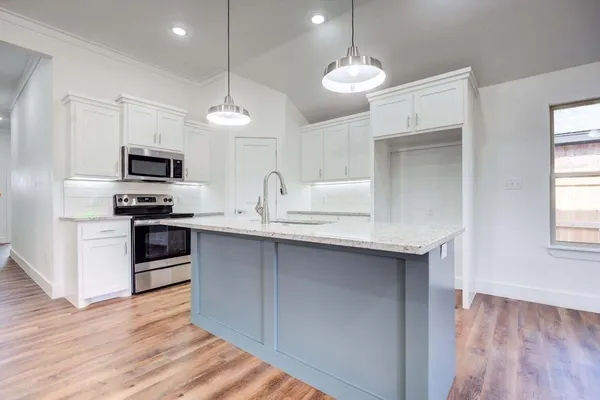 a kitchen with granite countertop a stove a sink and a refrigerator