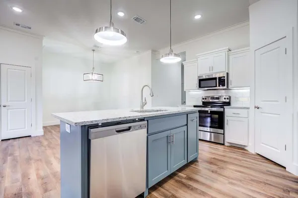 a kitchen with a sink stainless steel appliances and wooden floor