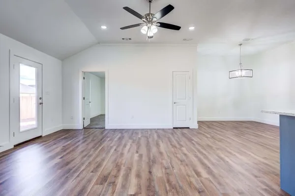 a view of an empty room with window and wooden floor