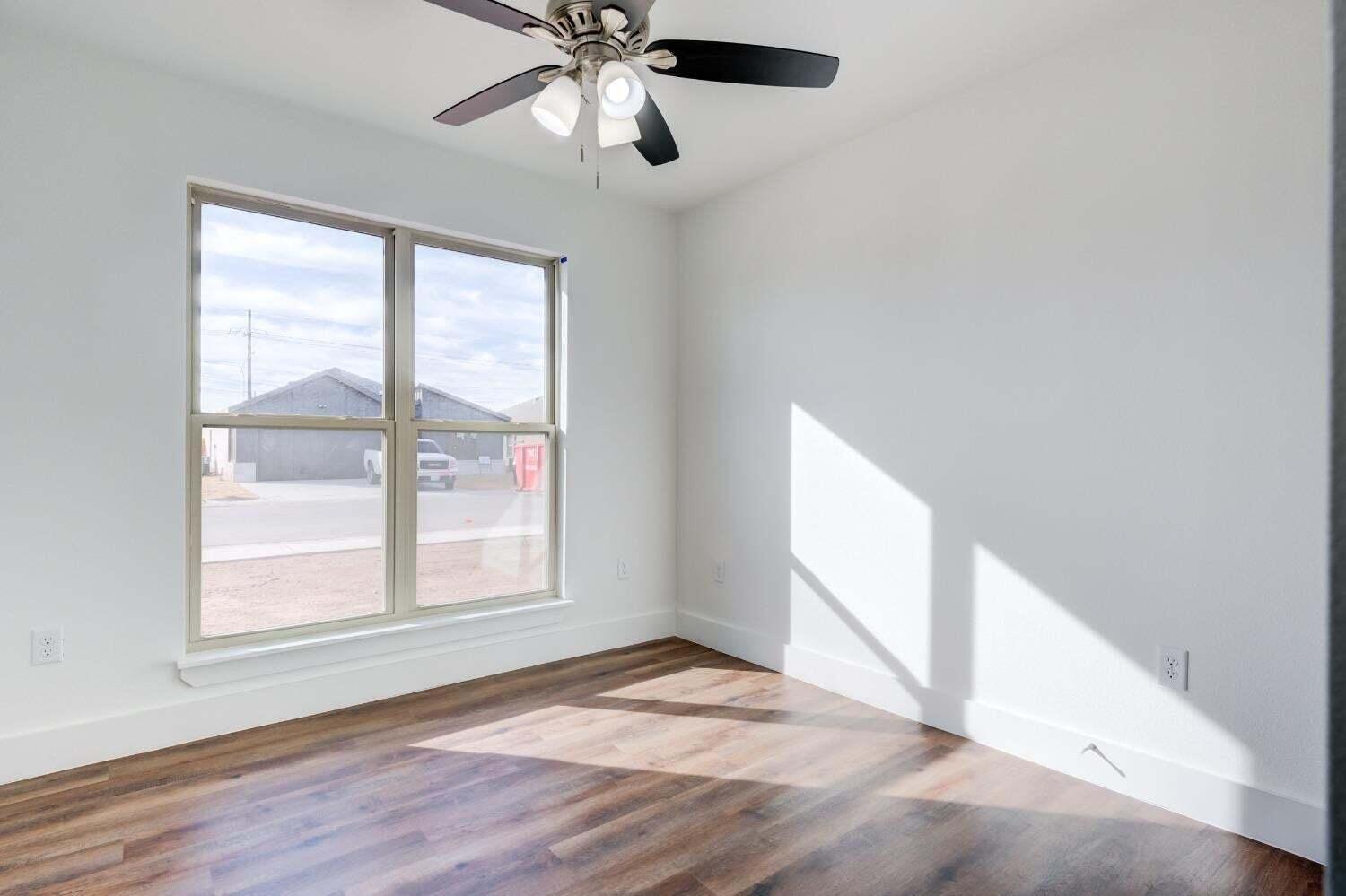 7808 97th Street Lubbock, TX 79424 - Photo 3 of 38 an empty room with wooden floor fan and windows