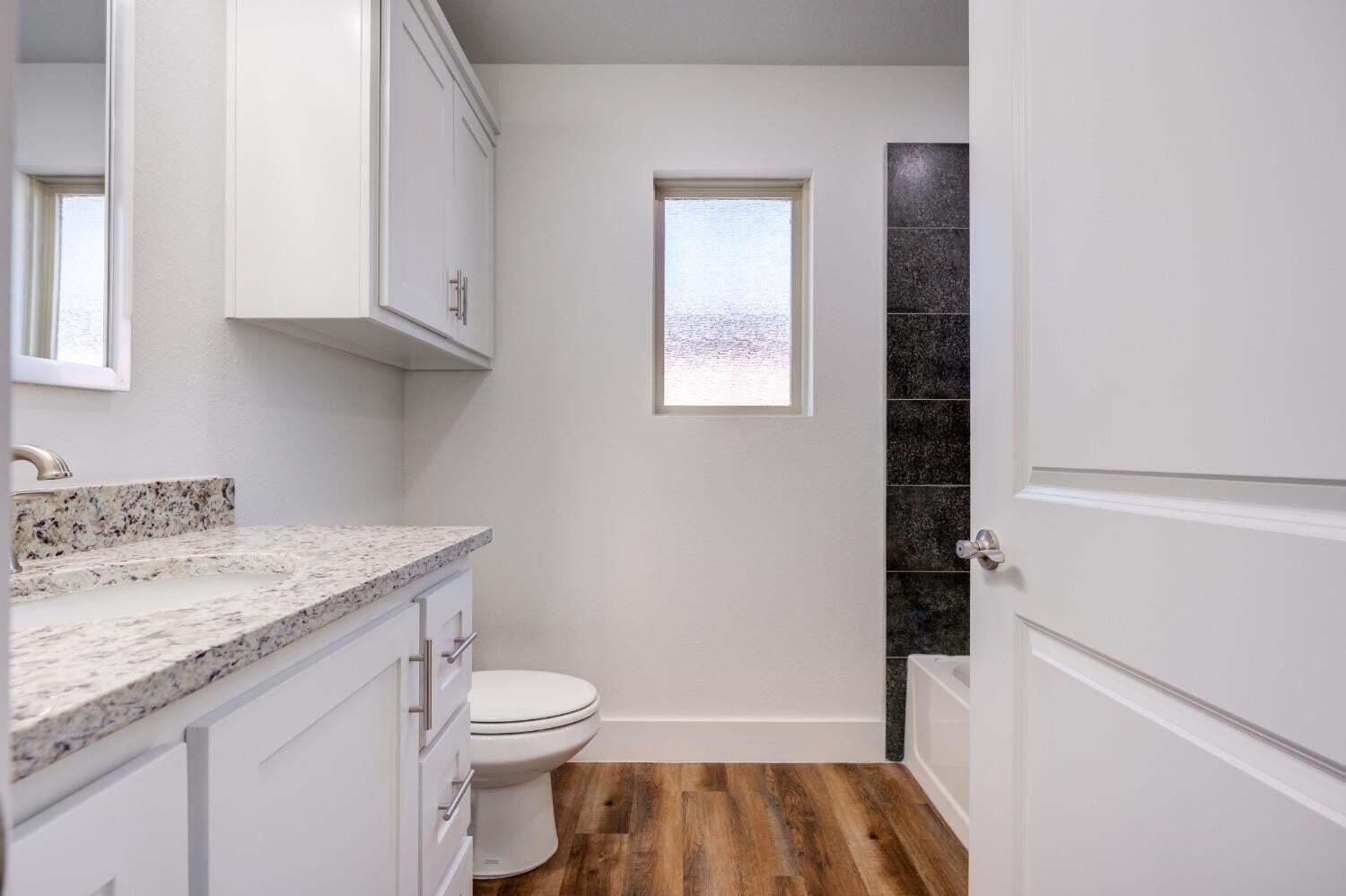 7808 97th Street Lubbock, TX 79424 - Photo 5 of 38 a bathroom with a granite countertop sink toilet and shower