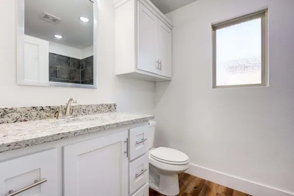 a bathroom with a granite countertop sink a toilet and a mirror