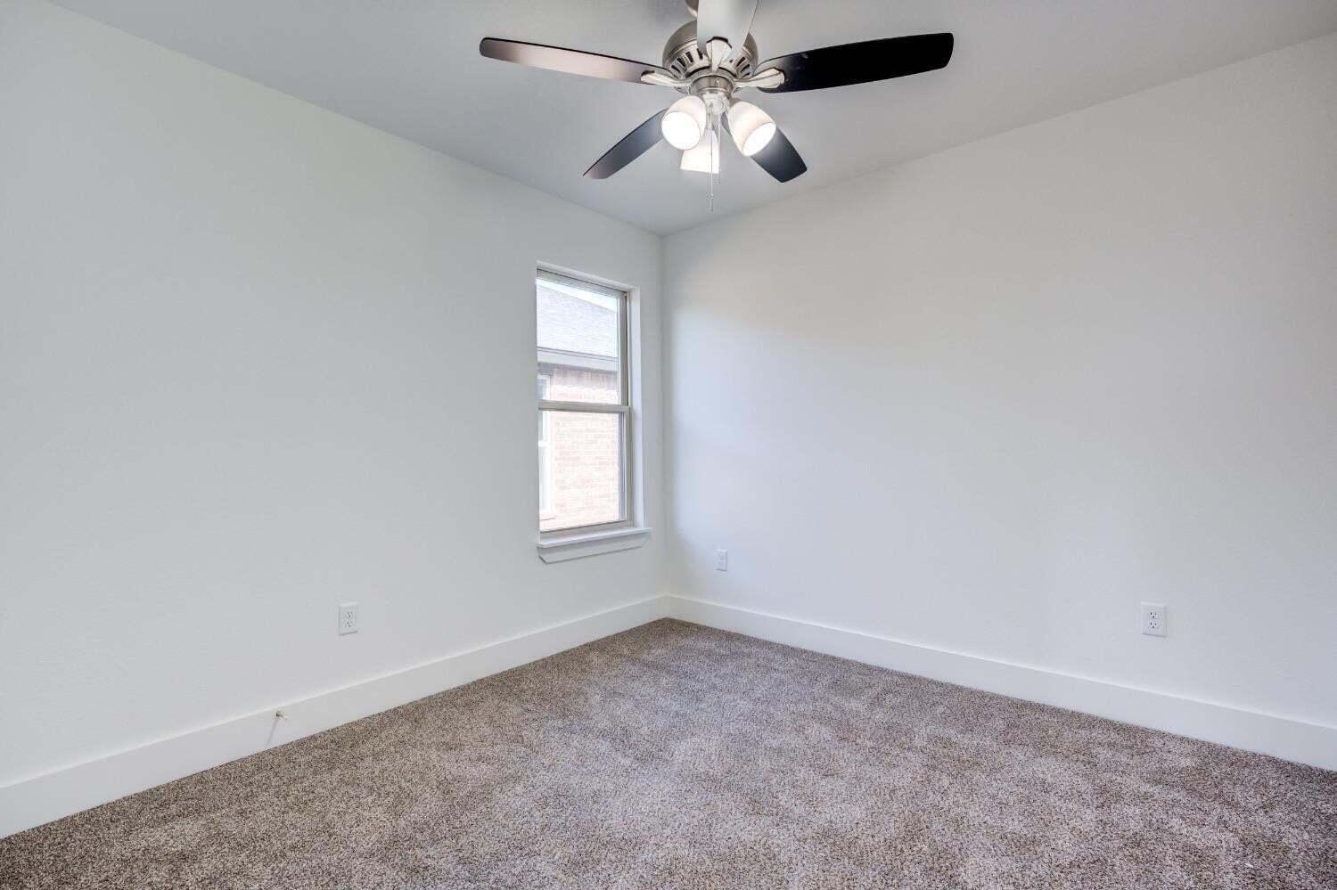 7808 97th Street Lubbock, TX 79424 - Photo 7 of 38 an empty room with a window and a fan