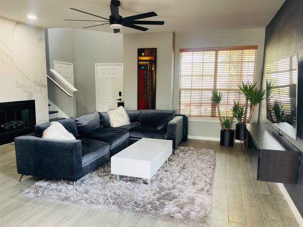 516 Angela Lane Euless, TX 76039 - Photo 3 of 39 Living room featuring light wood finished floors, stairway, a premium fireplace, and a ceiling fan