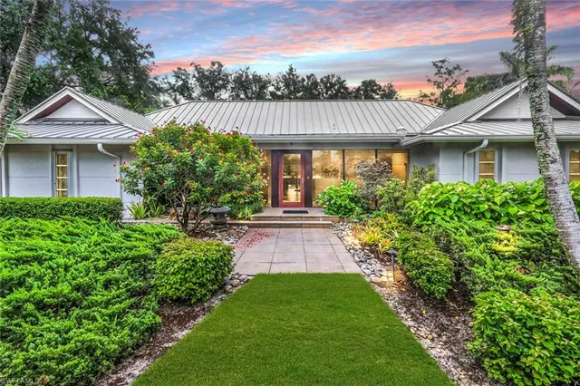 a front view of a house with a yard and potted plants