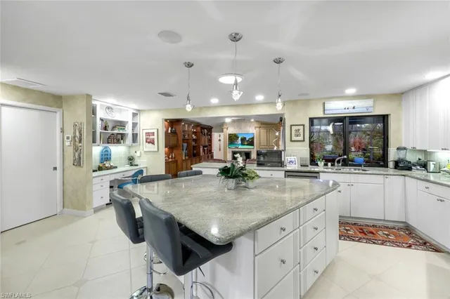 a kitchen with stainless steel appliances kitchen island granite countertop a table chairs sink and cabinets