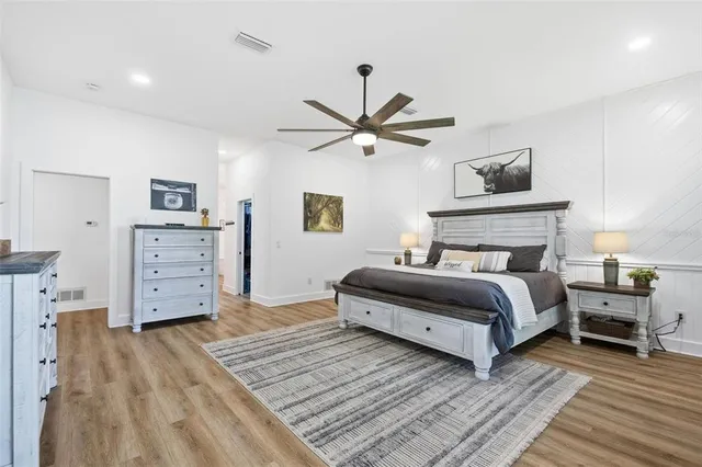 a spacious bedroom with a large bed a chandelier and windows