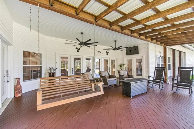 a backyard of a house with table and chairs with plants and large tree
