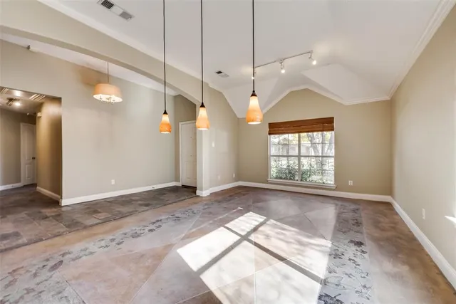 a view of an empty room with window and chandelier fan