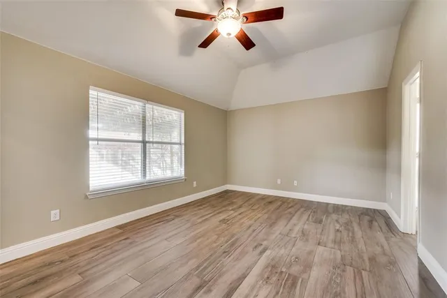 an empty room with wooden floor ceiling fan and windows