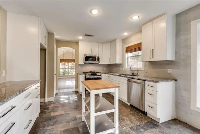a kitchen with white cabinets and appliances