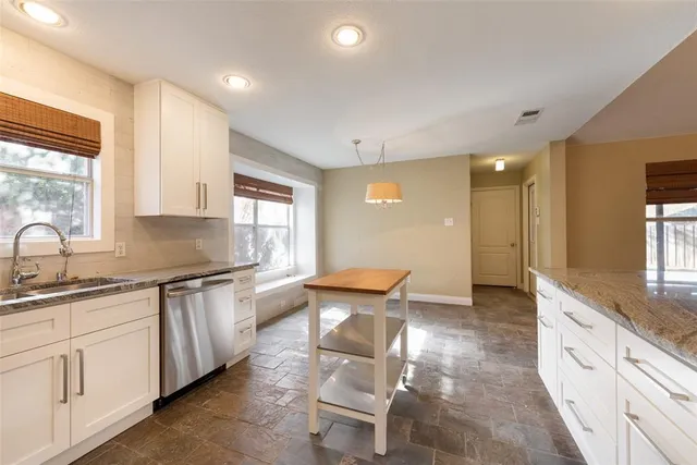 a large kitchen with granite countertop a sink and white cabinets