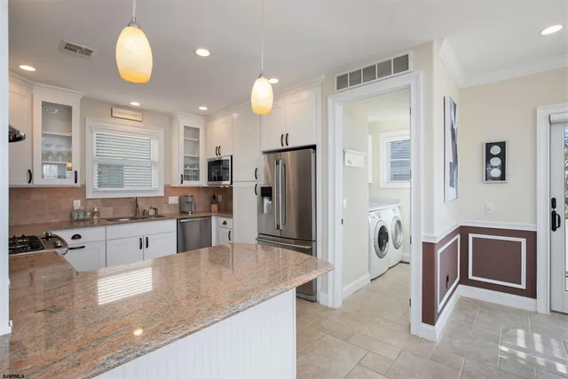 a large kitchen with granite countertop a large counter top stainless steel appliances and cabinets
