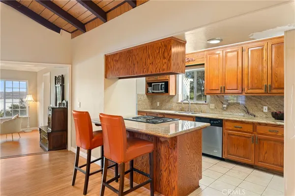 a kitchen with stainless steel appliances granite countertop a table chairs sink and cabinets