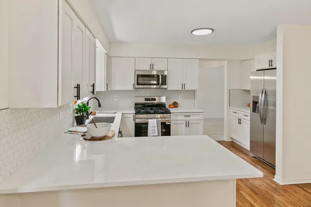 a kitchen with stainless steel appliances a stove a sink and white cabinets