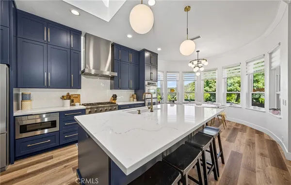 a large kitchen with stainless steel appliances a large center island attached withe living room