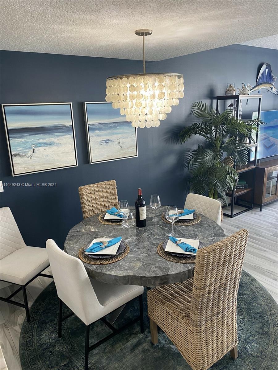 155 Soriano Drive, Unit 155 Jupiter, FL 33458 - Photo 8 of 29 a view of a dining room with furniture a chandelier and wooden floor