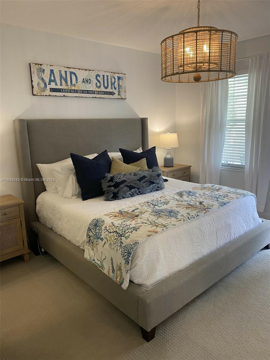 155 Soriano Drive, Unit 155 Jupiter, FL 33458 - Photo 9 of 29 a large bed sitting in a bedroom next to a chandelier