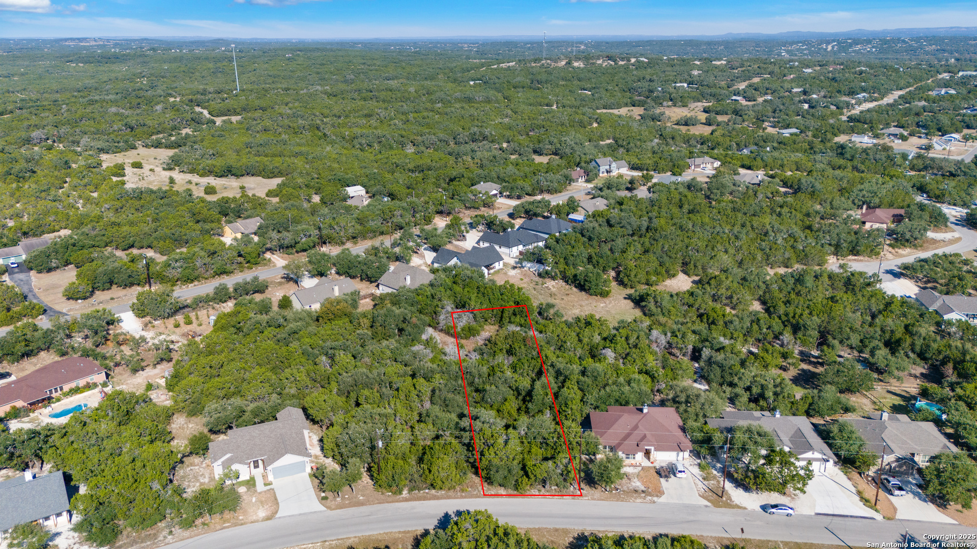 an aerial view of residential houses with outdoor space and trees