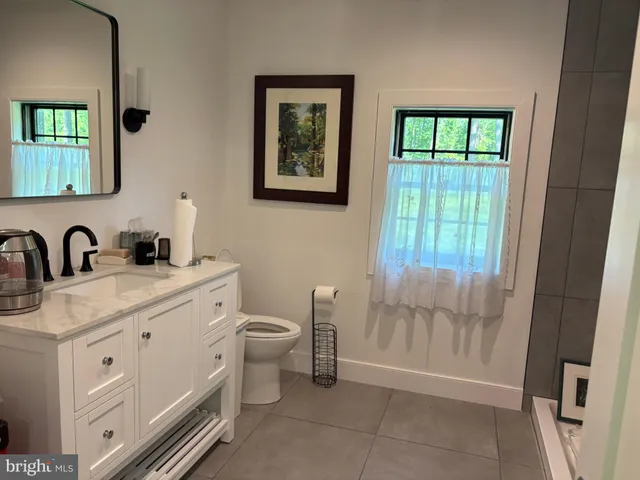 a bathroom with a granite countertop sink a toilet and a window