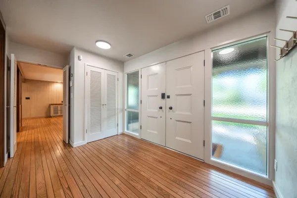 an empty room with wooden floor and windows