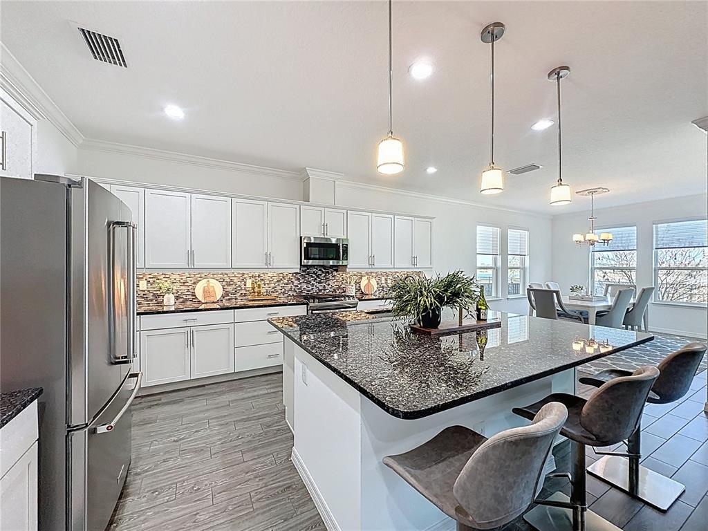 178 Silver Maple Road Groveland, FL 34736 - Photo 11 of 72 a kitchen with kitchen island granite countertop a table chairs stove and refrigerator