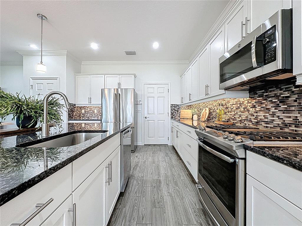 178 Silver Maple Road Groveland, FL 34736 - Photo 12 of 72 a large kitchen with stainless steel appliances granite countertop a stove a sink and a microwave
