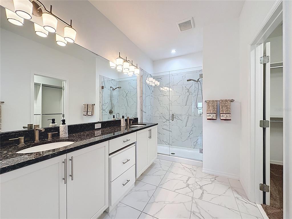 178 Silver Maple Road Groveland, FL 34736 - Photo 19 of 72 a spacious bathroom with a granite countertop sink a mirror and a shower