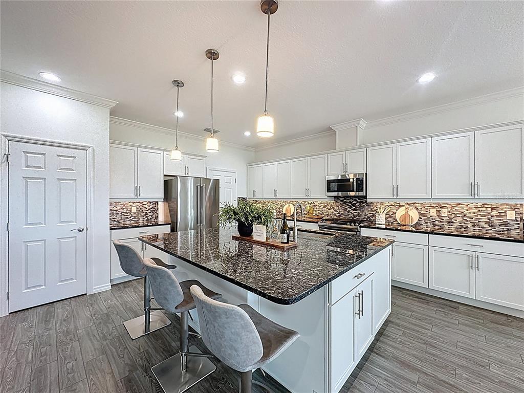 178 Silver Maple Road Groveland, FL 34736 - Photo 10 of 72 a kitchen with stainless steel appliances granite countertop a stove top oven a refrigerator a sink and white cabinets with wooden floor