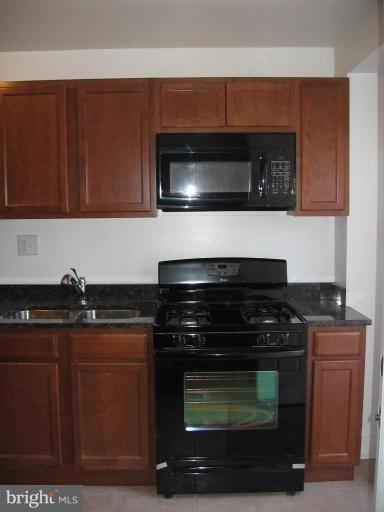 2209 Monticello Road Baltimore, MD 21216 - Photo 13 of 30 a kitchen with granite countertop a stove and a microwave