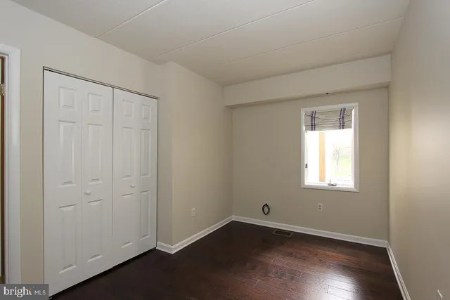 an empty room with wooden floor closet and windows