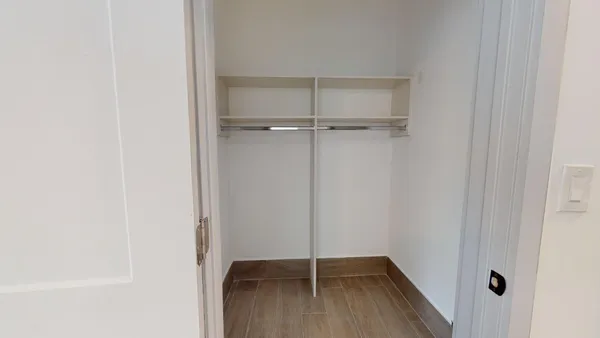 a view of room with walk in closet with wooden floor