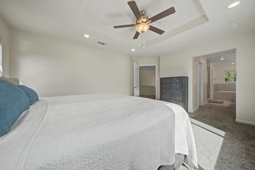 13871 Petersen Ranch Drive Pine Grove, CA 95665 - Photo 39 of 74 a spacious bedroom with a large bed and a chandelier