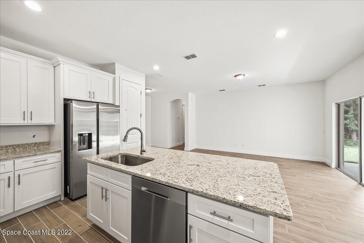 1296 Daton Road Southwest Palm Bay, FL 32908 - Photo 11 of 32 a kitchen with granite countertop kitchen island stainless steel appliances a sink stove refrigerator and cabinets