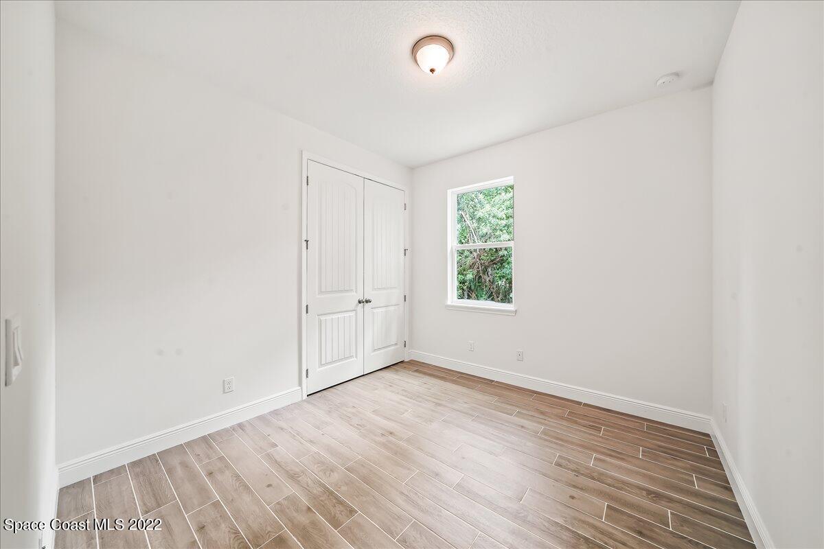 1296 Daton Road Southwest Palm Bay, FL 32908 - Photo 25 of 32 an empty room with wooden floor and windows